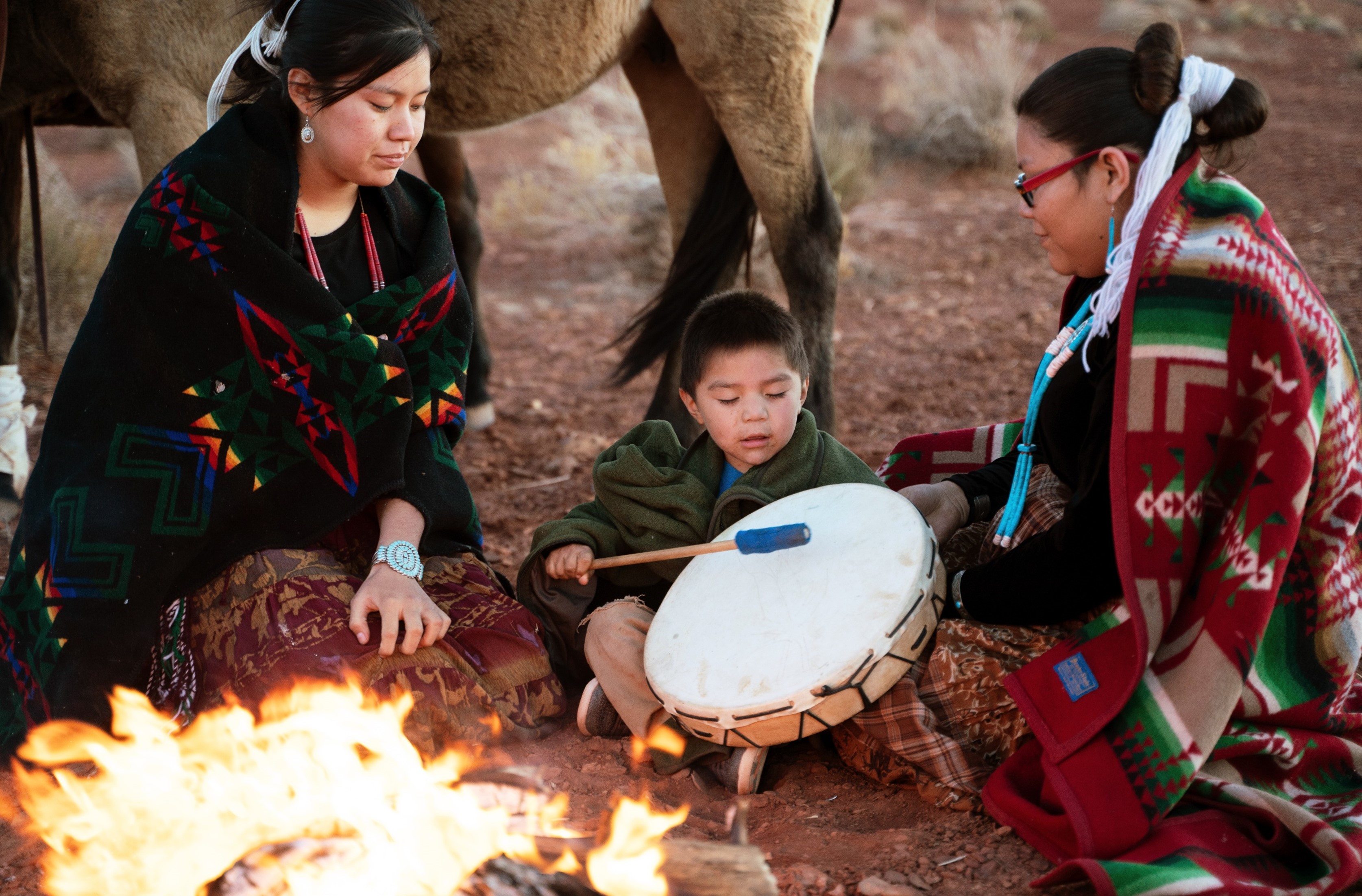 Native American grandmother teaching grandson to play drum