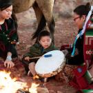 Native American grandmother teaching grandson to play drum